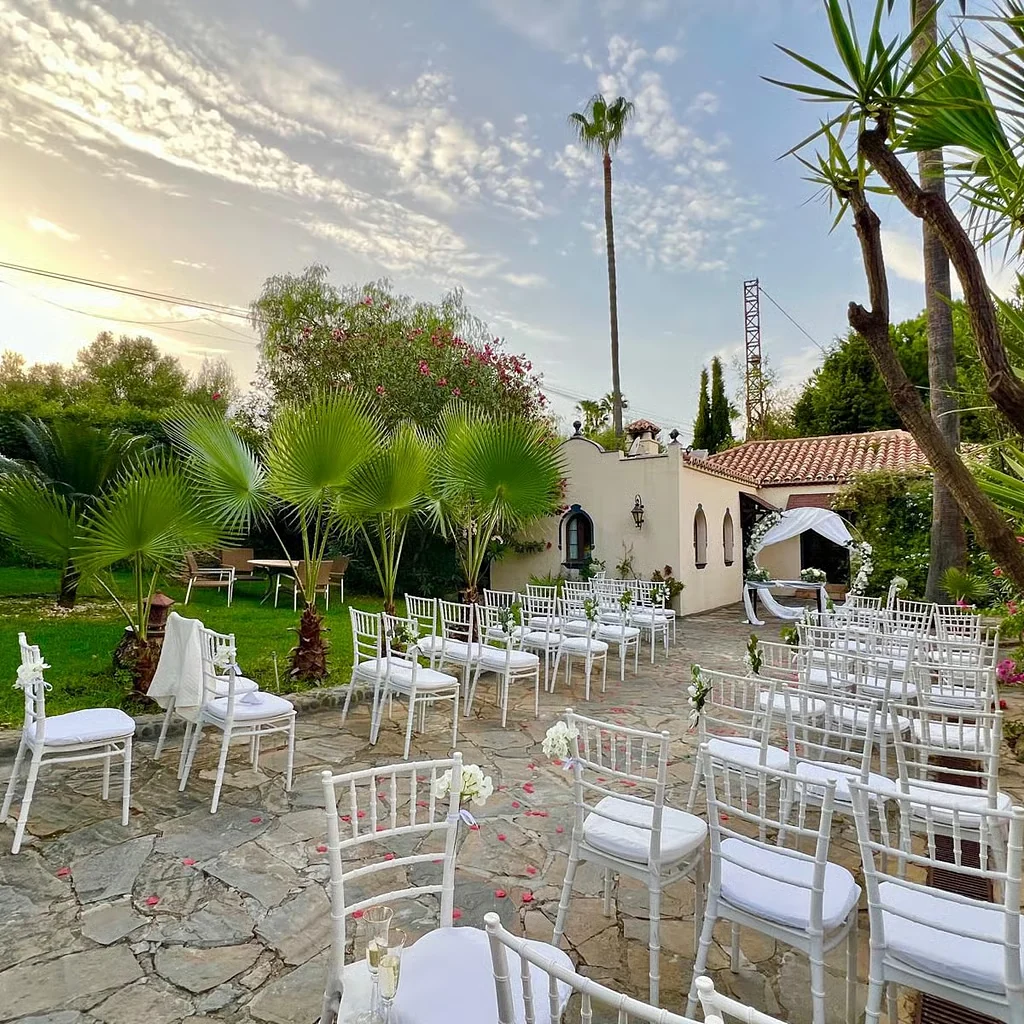 Chairs set for a ceremony among the palms as the sun lowers